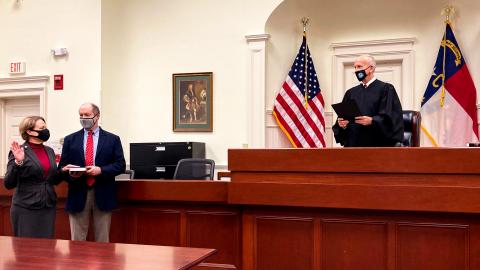 Chief Judge Donna Stroud (left) stands with her husband, J. Wilson Stroud, while Chief Justice Paul Newby administers her oath of office.