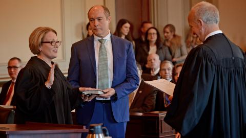 Chief Judge Donna Stroud (left) takes the oath of office while her husband holds the Bible.
